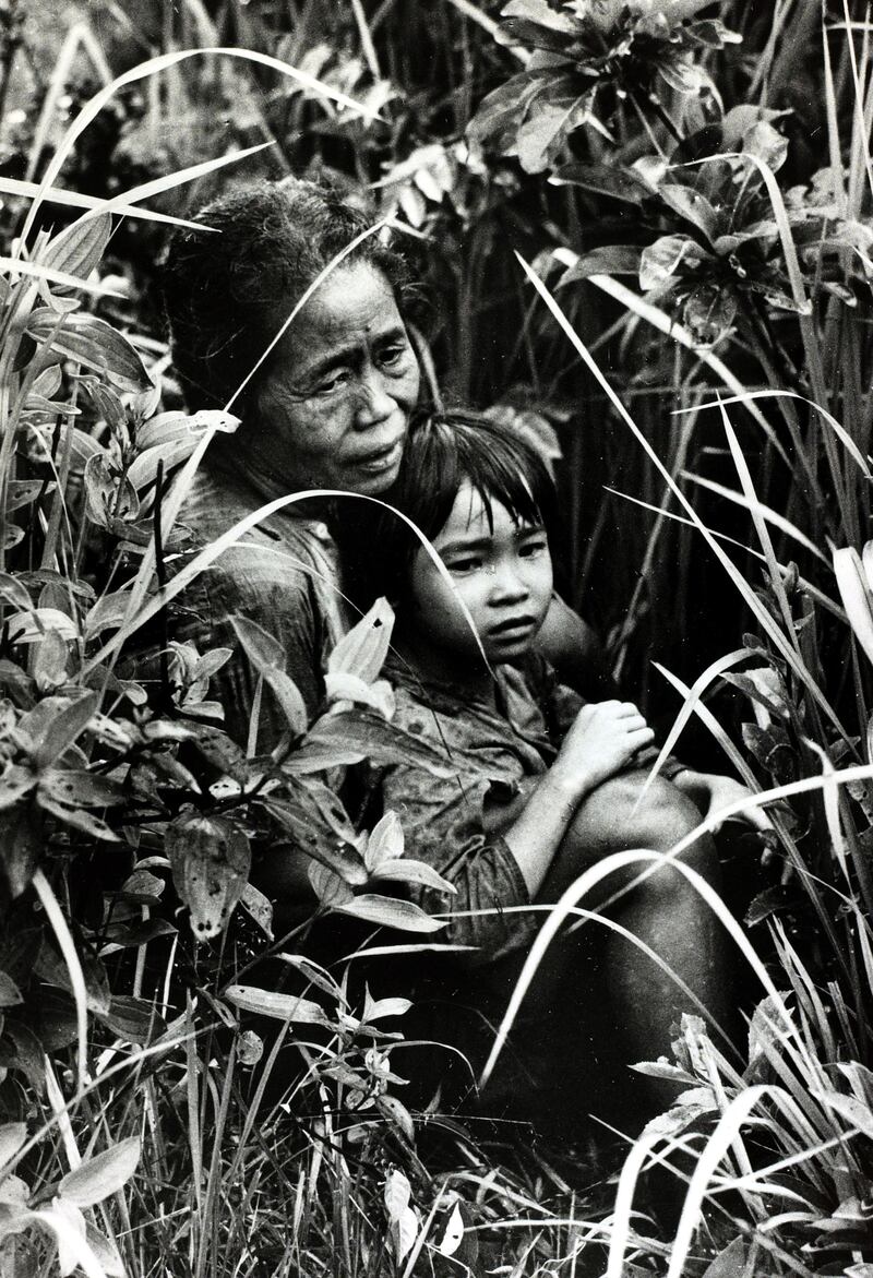 In Chu Lai, South Vietnam, an old Vietnamese woman and her grandchild take cover in the fields as a battle ensues around them circa 1968. Photograph: Rolls Press/Popperfoto/Getty Images