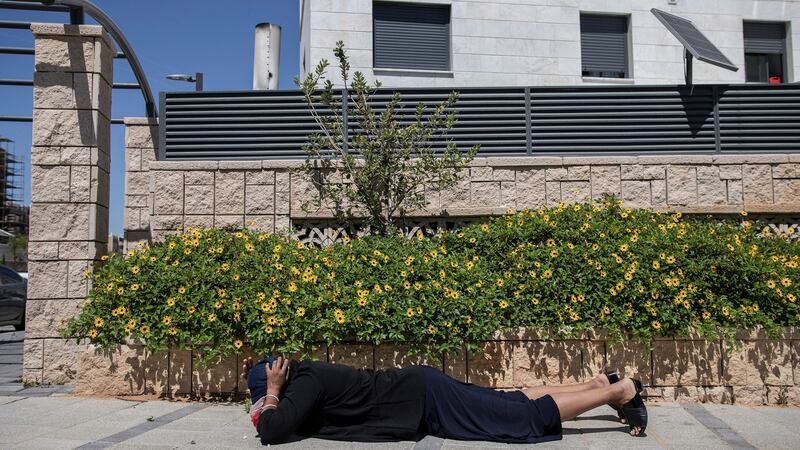 An Israeli woman takes cover during    rocket fire from Gaza in the city of Ashkelon, Israel. Photograph: Dan Balilty/The New York Times