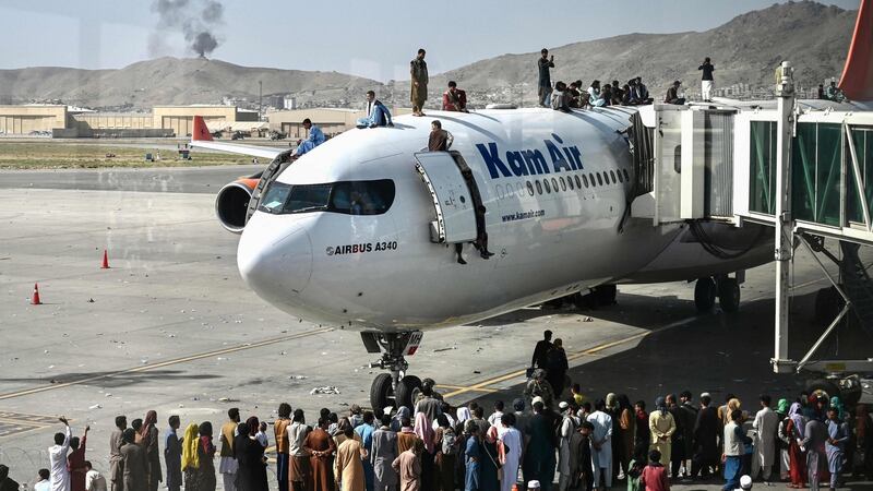 People climb atop an aeroplane  at the Kabul airport on Monday as thousands of people try to flee the Taliban’s feared hardline brand of Islamist rule. Photograph: Wakil Kohsar/AFP via Getty Images