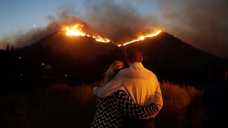 Roger Bloxberg and his wife Anne hug as they watch a wildfire on a hilltop near their home  in West Hills, California. Photograph: Marcio Jose Sanchez/AP Photo