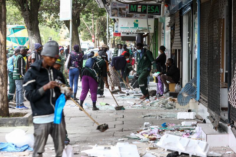 People clean up a sidewalk littered with broken glass in Nairobi, Kenya, following protests. Photograph: Daniel Irungu/EPA