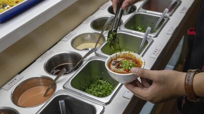 A diner selects condiments at a Haidilao restaurant. Photograph; Gilles Sabrié/ The New York Times