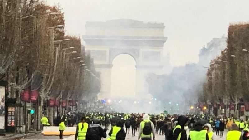 The gilets jaunes (yellow vests) protest on the  Champs-Élysées beneath a fog of tear gas. Photograph: Garret Fitzgerald