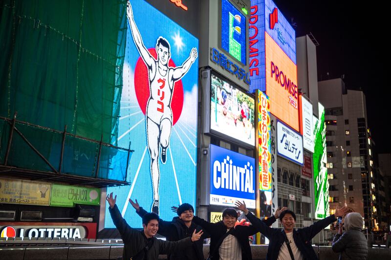 People pose for photo in front of the Glico Man sign in the Dotonbori area of Osaka. Photograph: Philip Fong/AFP via Getty