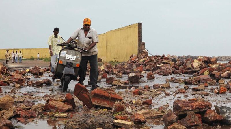 People walk among debris from a broken wall after it was damaged by a wave brought by Cyclone Phailin at a fishing harbour in Visakhapatnam district in the southern Indian state of Andhra Pradesh today. Photograph: R Narendra/Reuters