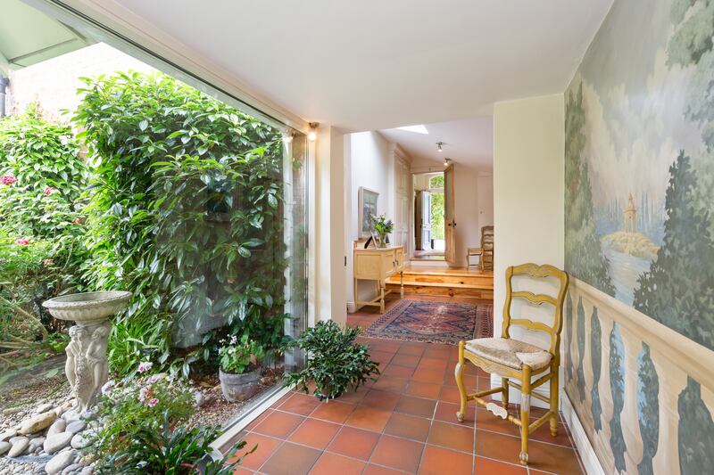 A corridor connecting the house to the garden room has a mural on one side with glazing on the other