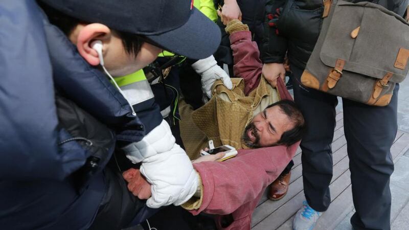Security personnel detain Kim Ki-jong, a member of a pro-Korean unification group who attacked the US ambassador to South Korea Mark Lippert at a public forum, in central Seoul. Photograph: Kim Ju-sung/Yonhap/Reuters
