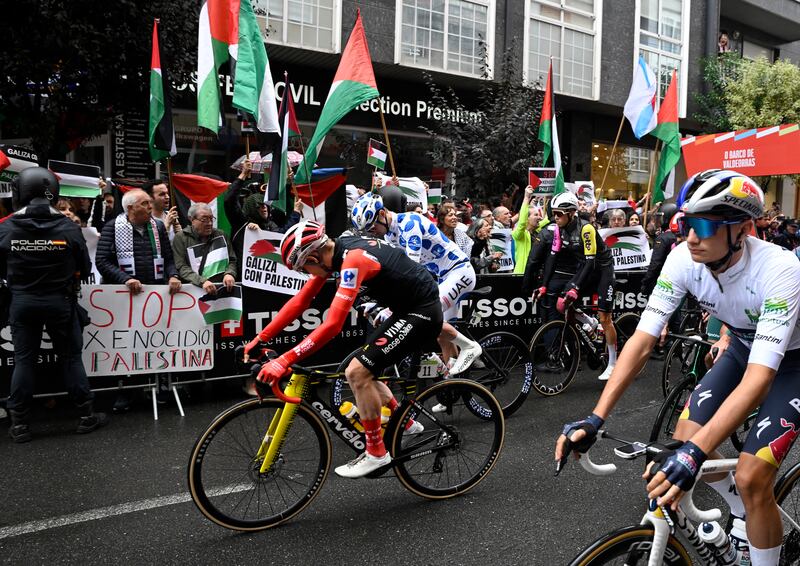 Protesters wave Palestinian flags as riders take the start of the 17th stage of the Vuelta a Espana. Photograph: Miguel Riopa/AFP via Getty Images         