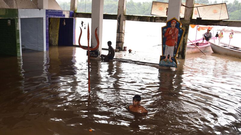 An Indian man wades through a submerged temple near the flooded Narmada river, in Jabalpur, India. Photograph: Sanat Kumar Singh/EPA
