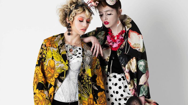 Claire wears Dries Van Noten coat €887.50 (sale price), Samui, Cork; polka dot blouse, €199, and trousers, €179, both Joseph Ribkoff at Sheena’s Boutique, Cork. Handpainted corset, stylist’s own; flamingo headpiece, €135, Mary Ginnifer Designs; earrings, €35, Diamond Buyer’s Club at Sheena’s Boutique, Cork; chain Rothlu by Frances McGonigle, rothlu.ie. Lara wears jacket, €309, and flower embellished tee, €35, both Joseph Ribkoff at Sheena’s Boutique, Cork; polka dot shorts, €52, Topshop,  Cork; earrings Rothlu, rothlu.ie. Props: The Village Hall, Cork, Declan O’Meara Art; Williot Menswear, Cork.