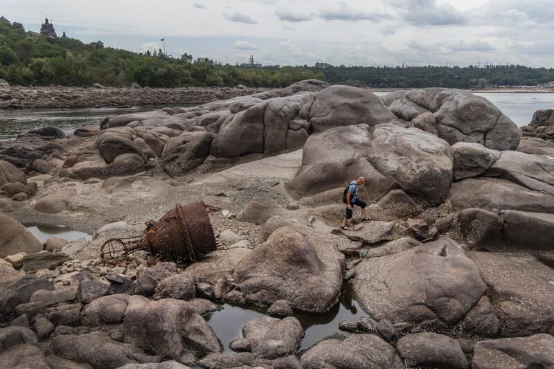 Oleksandr Shkalikov, a Ukrainian tank driver, scrambles over the surreal landscape revealed after the Kakhovka dam was destroyed, in the Zaporizhzhia region, Ukraine. Photograph: David Guttenfelder/New York Times
                      