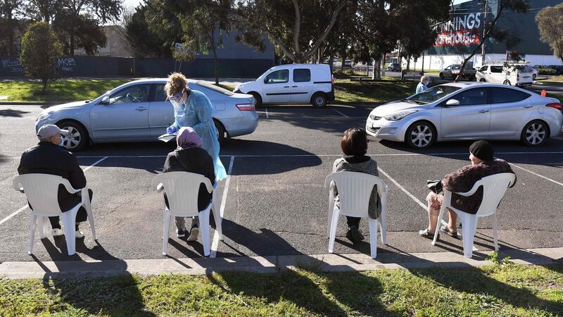 People wait in chairs and cars during testing for Covid-19  at a drive- and walk-through pop-up venue in Melbourne. Photograph: William West/AFP via Getty Images