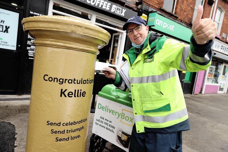 CONGRATULATIONS KELLIE: Local postman Martin Bowden at a postbox outside Summerhill post office in Dublin city, which has been painted gold to mark local hero Kellie Harrington's Olympic gold medal. Photograph: Maxpix Dublin