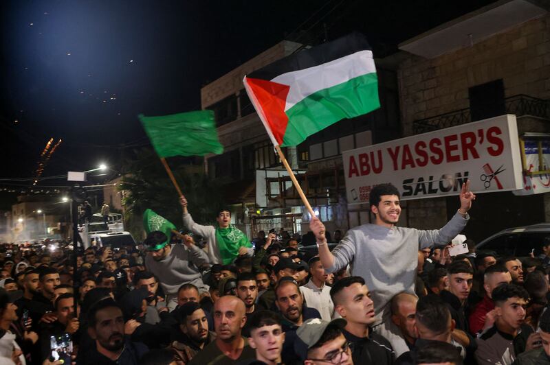 Palestinian prisoners (wearing grey jumpers) who were released from the Israeli Ofer military facility in exchange for hostages freed by Hamas in Gaza wave flags and chant slogans as they are paraded in Baytunia in the occupied West Bank on Friday. Photograph: Ahmad Gharabli/AFP via Getty Images