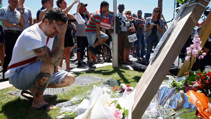A man cries near bouquets of flowers close to the scene where a truck ran into a crowd killing scores and injuring more who were celebrating the Bastille Day. Photograph: Reuters