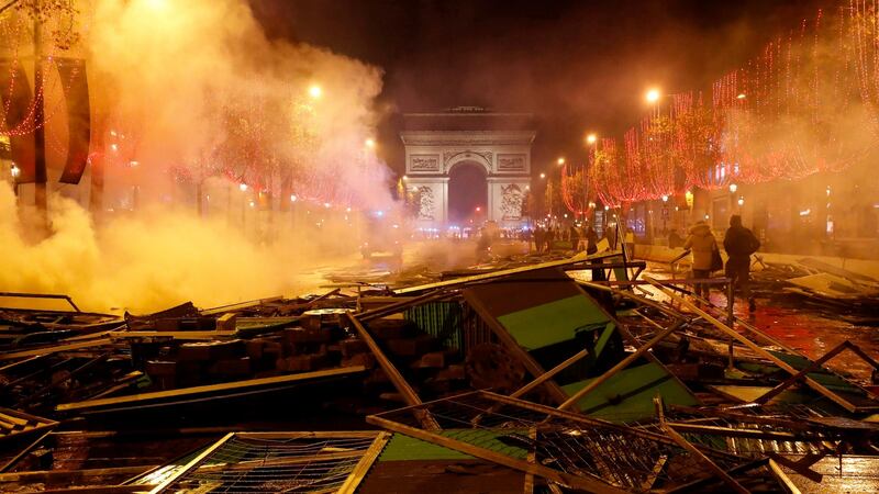 Pedestrians walk around  burnt protest detritus after it had been extinguished, near the Arc de Triomphe  in Paris, on Saturday, in the wake of  a gilets jaunes protest.  Photograph: Francois Guillot/AFP/Getty Images