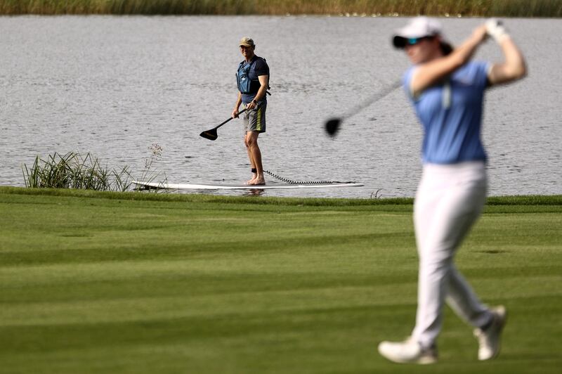 A paddle boarder looks on as Leona Maguire drives down the 18th fairway at Drumoland Castle. Photograph: Ben Brady/Inpho
