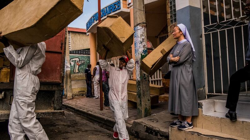 A nun looks on as workers from the St Luke Foundation work to collect abondoned bodies from a funeral home in Port-au-Prince, Haiti. Photograph: Daniel Berehulak/The New York Times