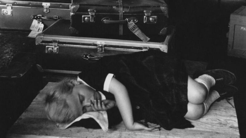 Tiring journey: a girl who has just arrived at Ellis Island curls up on a packing case for a nap, in 1950. Photograph: Ernst Haas/Hulton/Getty