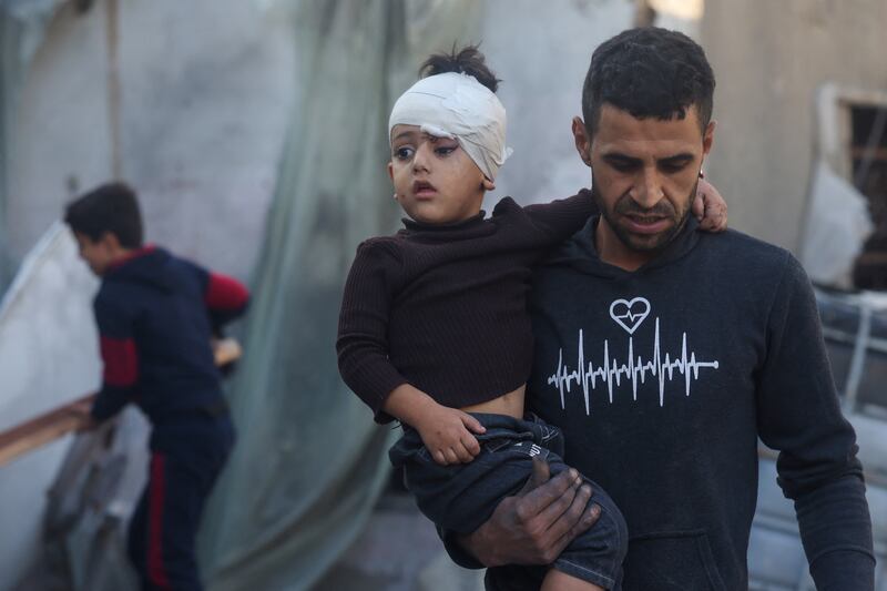 A Palestinian man carries a child injured during Israeli bombardment in Rafah, in the southern Gaza Strip, on Saturday. Photograph: Mohammed Abed/AFP via Getty Images