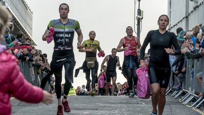 Competitors run from the beach to the transition point to pick up their bikes during the Wales Ironman.