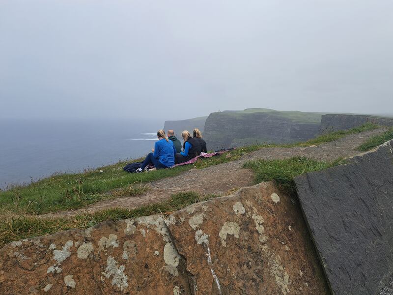 A family have a picnic along an unprotected cliff edge, beside a 700ft drop, on the Cliffs of Moher Walking Trail, metres away from the safe pathway. Photograph: Andrew Hamilton