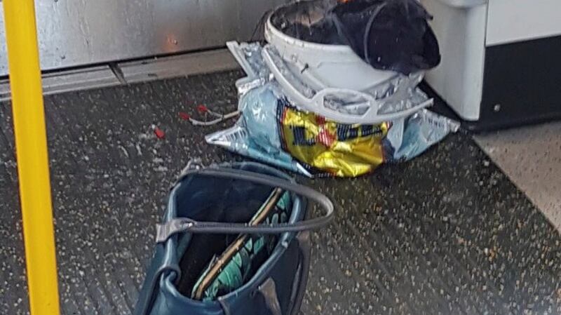 Personal belongings and a bucket with an item on fire inside it on the floor of an underground train carriage at Parsons Green station in west London.