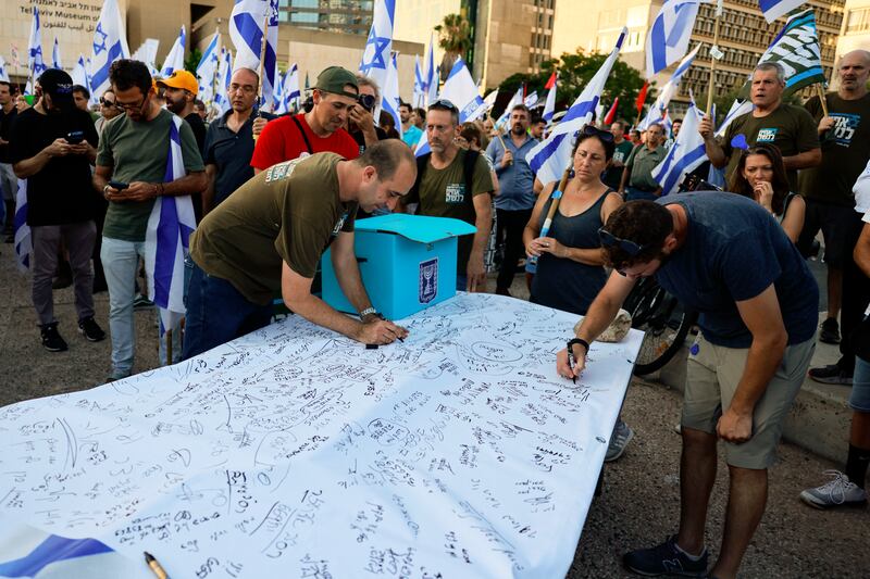 Israeli military reservists in Tel Aviv sign a declaration announcing the suspension of their voluntary reserve duty in a protest against the government's judicial overhaul bill. Photograph: Menahem Kahana / AFP via Getty Images