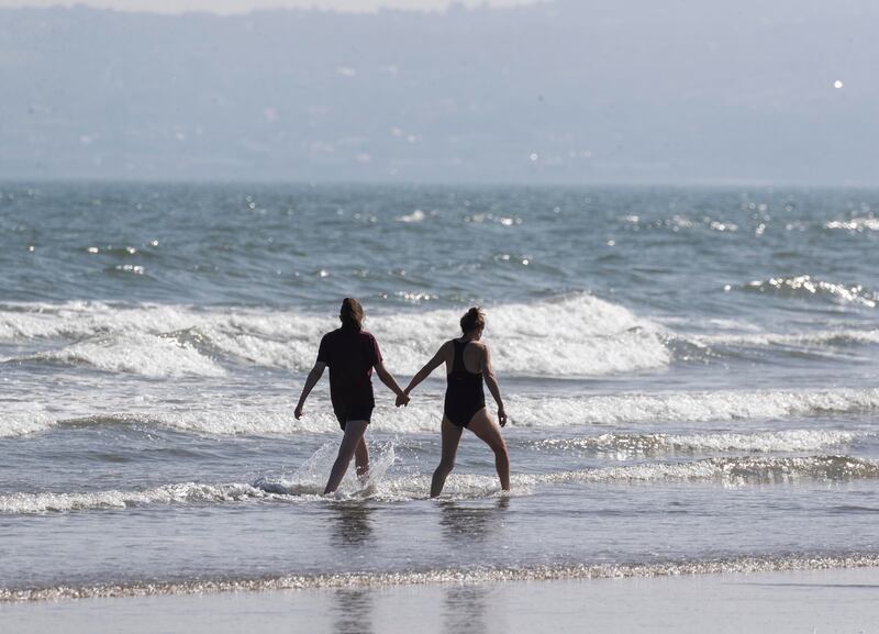 Beach goers wade in the waves on Portmarnock Beach. Photograph: Colin Keegan/Collins