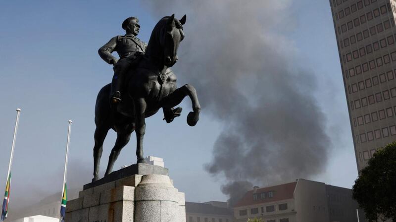 The statue of Louis Botha on horseback, the first prime minister of the Union of South Africa, is seen as smoke billows from the roof of a building at the South African Parliament precinct in Cape Town on January 2nd, 2022, during a fire incident. Photograph: Marco Longari/ AFP via Getty Images