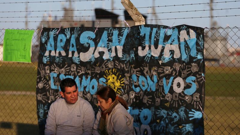 A couple sit in front of a sign  supporting  the 44 crew members of the missing  ARA San Juan submarine outside an Argentine naval base in Mar del Plata, Argentina. Photograph: Marcos Brindicci/Reuters