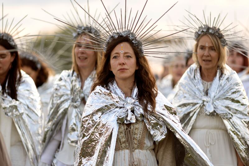 Women in a ritual procession in front of the unlit bonfire
