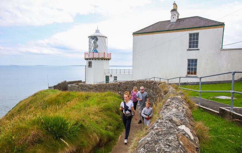 Walkers trek along the cliff path beside Blackhead Lighthouse in Co Antrim. Photograph: Paul Faith