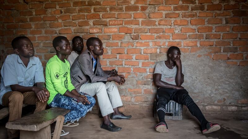 Men watch an English-language screening of the Dominic Ongwen ICC verdict, in his home village of Coorom, northern Uganda. Photograph:  Sally Hayden