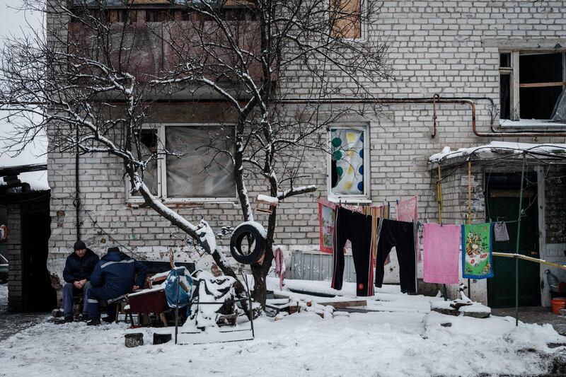 Men sit at the entrance of their apartment building in Lyman, Donetsk region. Photograph: Yasuyoshi Chiba/AFP via Getty Images