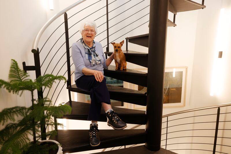 Grainne Wynne's mother Marie and dog Neuvo on the spiral staircase illuminated by Helestra from Lights.ie. The steps are now scorched black in the Japanese manner of shou sugi ban


