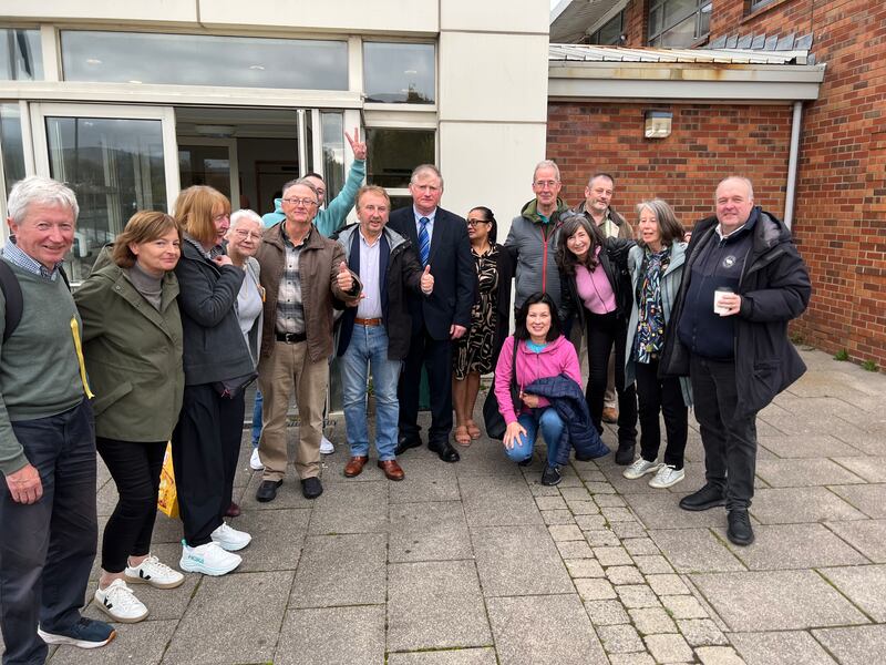 Mícheál MacGiobúin, centre, wearing black suit with blue shirt and blue tie, with supporters outside Tallaght District Court. Photo: Cian O'Connell