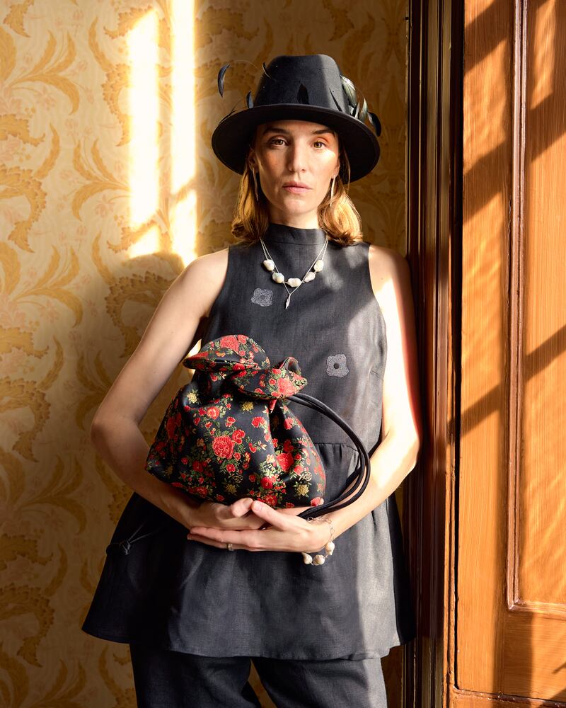 Black feather hat, €445, FAO Millinery;  embroidered top with flared peplum, €210, and black Nora pants, €290, both Jennifer Slattery; embroidered floral satin bag, €255, August Night; and earrings, €130, bracelet with pearl, €160, and necklace, €200, all from Inner Island