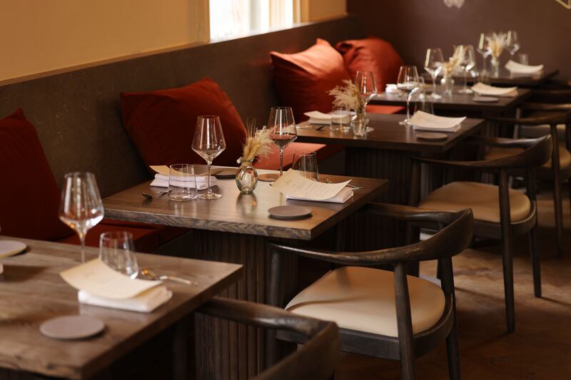 Amai by Viktor: An elegant space furnished with dark wood tables with chairs and banquettes