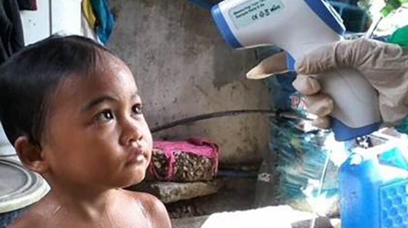 Four-year-old John Gador has his temperature checked in Sitio Marna