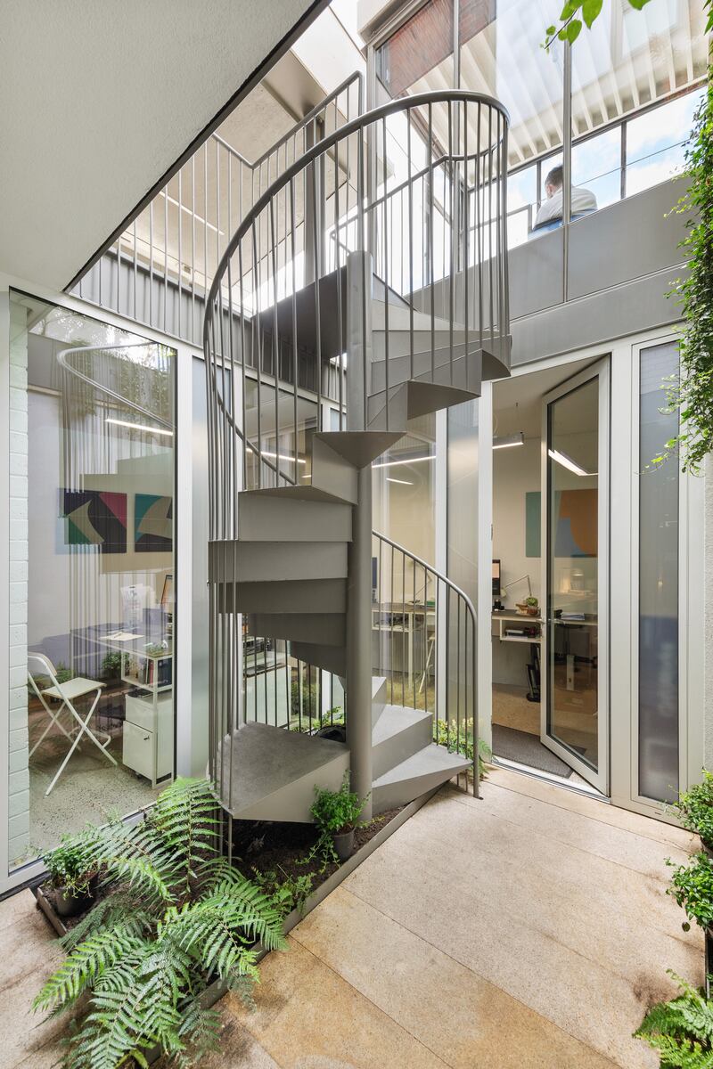 Painted stainless-steel staircase spirals from the front yard down to the basement