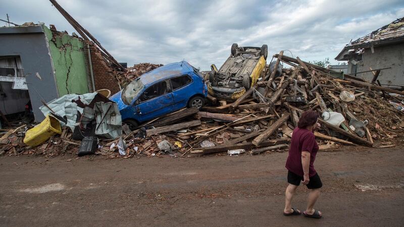 A woman walks past the debris of damaged buildings and cars in Mikulcice. Photograph: Michal Cizek/AFP via Getty Images