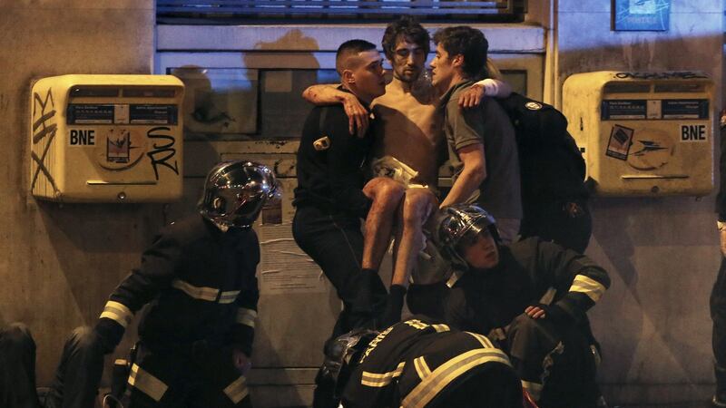French fire brigade members aid an injured individual near the Bataclan concert hall following fatal shootings in Paris. Photograph: Christian Hartmann /Reuters