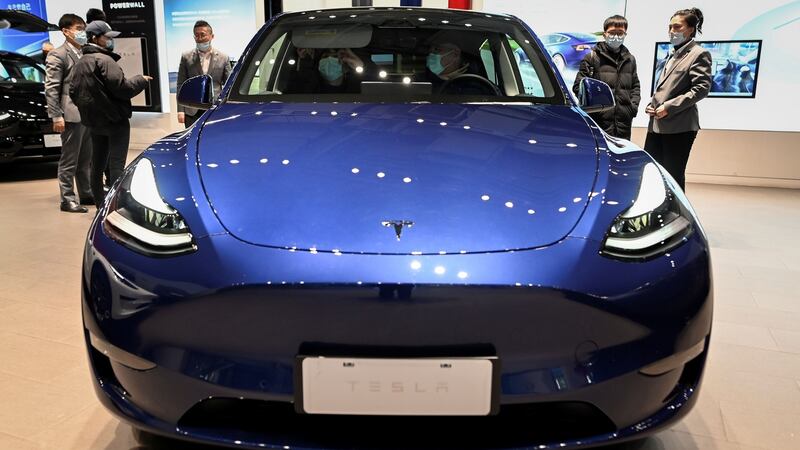 People look at a Tesla Model Y car at a Tesla showroom in Beijing .