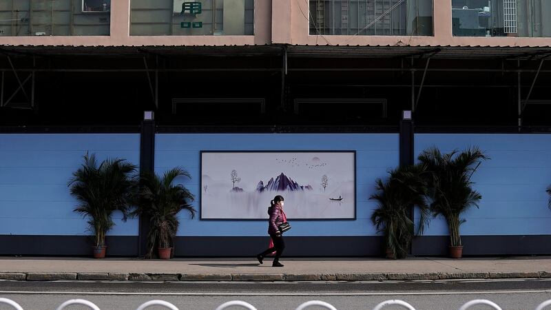 A resident walks past the Huanan Seafood Market last week in Wuhan, China. The market is now closed and hidden behind concrete walls. Photograph: Getty Images