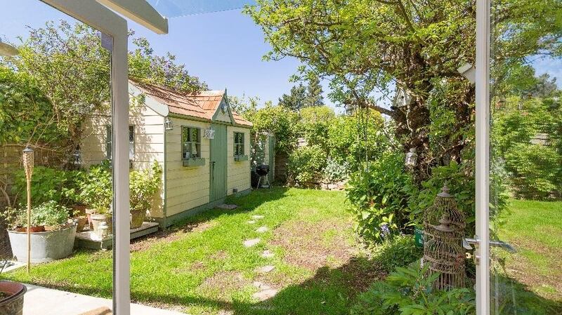French windows lead to the rear garden where there are blooming lilacs and Clematis, rose bushes and a small lawn