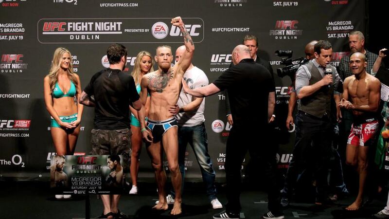 Conor McGregor salutes the crowd at the weigh-in for his fight against Diego Brandao (far right) . Photograph: James Crombie / Inpho
