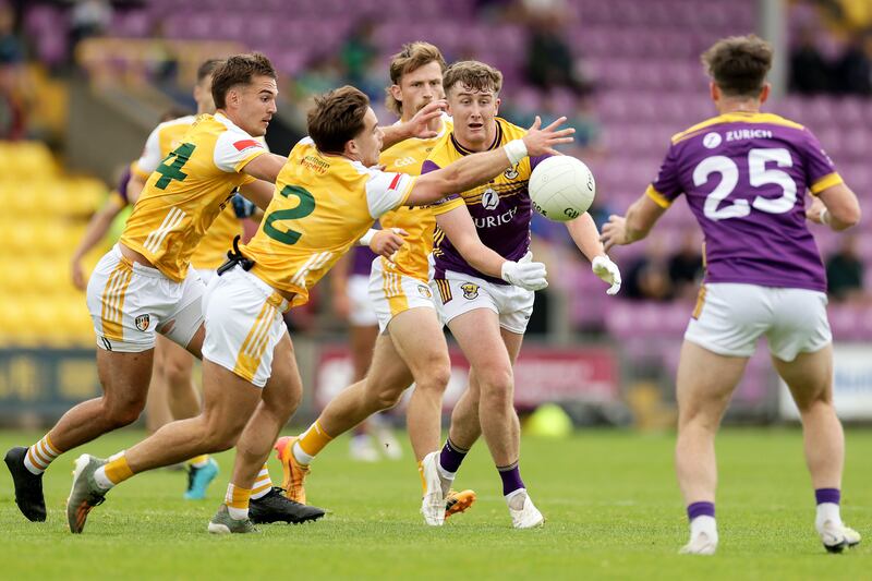 Wexford's Jack Higgins fists a pass despite the attention of Antrim's Eoghan McCabe and Joseph Finnegan during the Tailteann Cup preliminary quarter-final at Wexford Park on Sunday. Photograph: Laszlo Geczo/Inpho