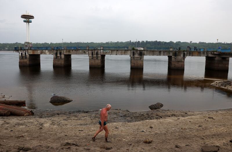 A man walks along the muddy banks exposed by the receding waters of the Dnipro river on the central beach of Zaporizhzhia, following the destruction of the Kakhovka dam. Photograph: Anatolii Stepanov/AFP via Getty