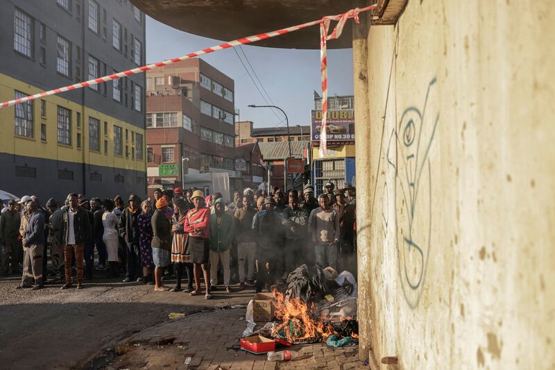 People look on as firefighters work at the scene of the fire in Johannesburg. Photograph: Michele Spatari/AFP via Getty Images